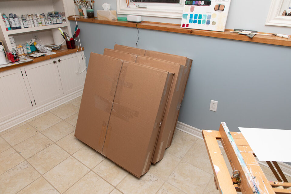 Several boxes containing paintings lean against a wall ready to be shipped