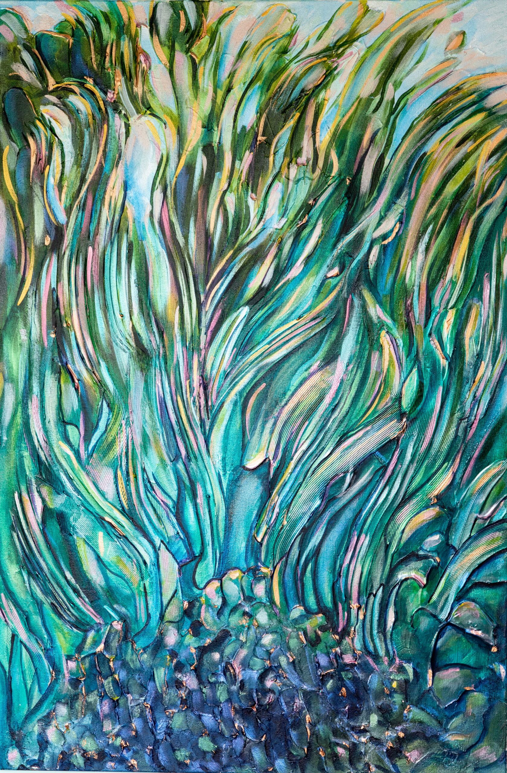 Green and gold grass rises dramatically toward the sky from a riverbed of blue pebbles.